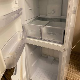 NATALIIA DEMCHUK - Wnętrze czystej, otwartej lodówki z przezroczystymi szufladami i półkami, widoczna regulacja temperatury.