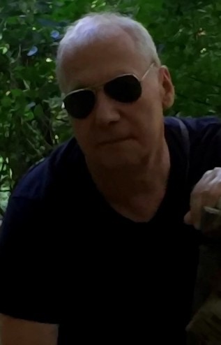 Portret starszego mężczyzny w ciemnych okularach na tle zieleni