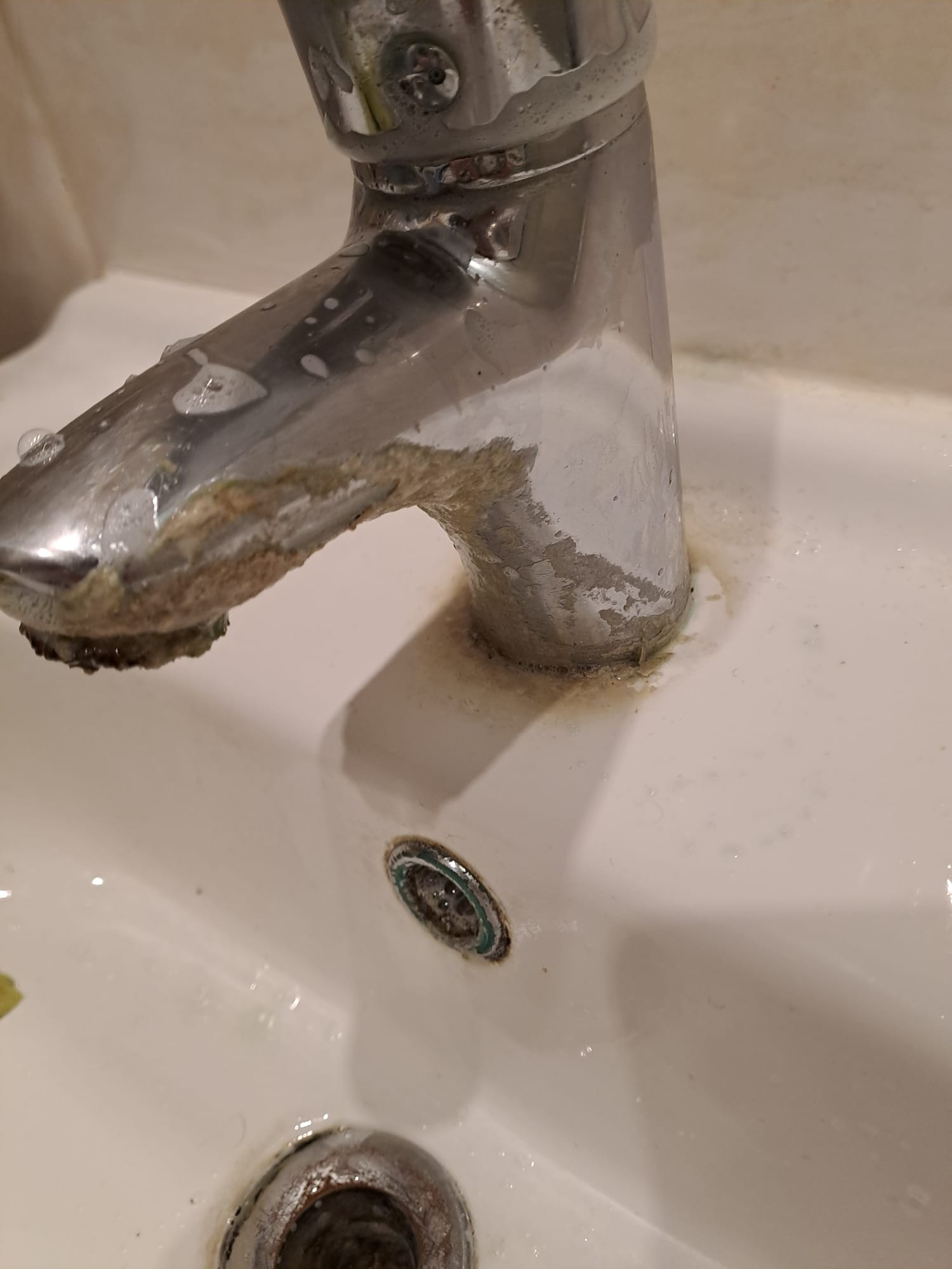 Z bliska: Zanieczyszczony osadem kran umywalkowy z resztkami mydlin i widocznym odpływem.
