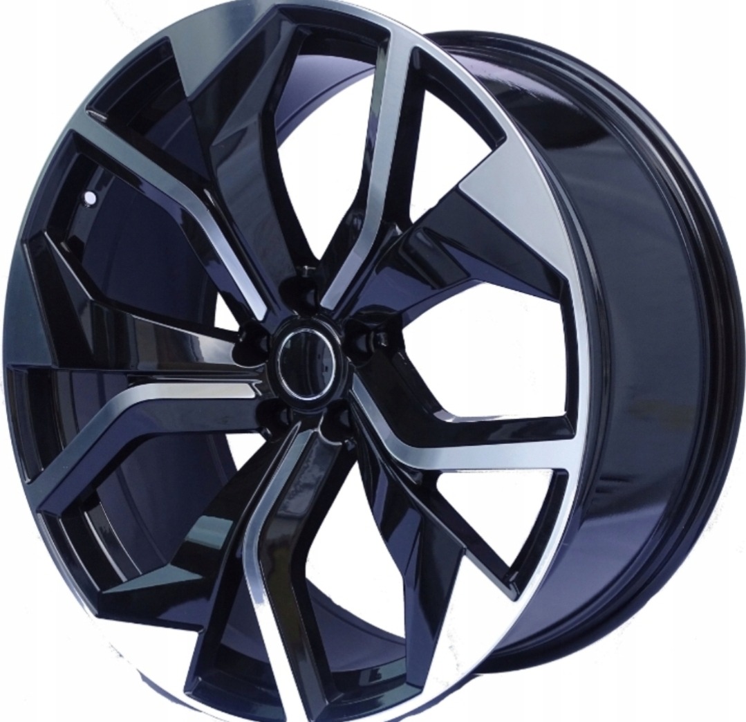 Błyszcząca, czarno-srebrna felga aluminiowa o geometrycznym wzorze, wyeksponowana na białym tle. Widoczne odbicia światła podkreślają detale.