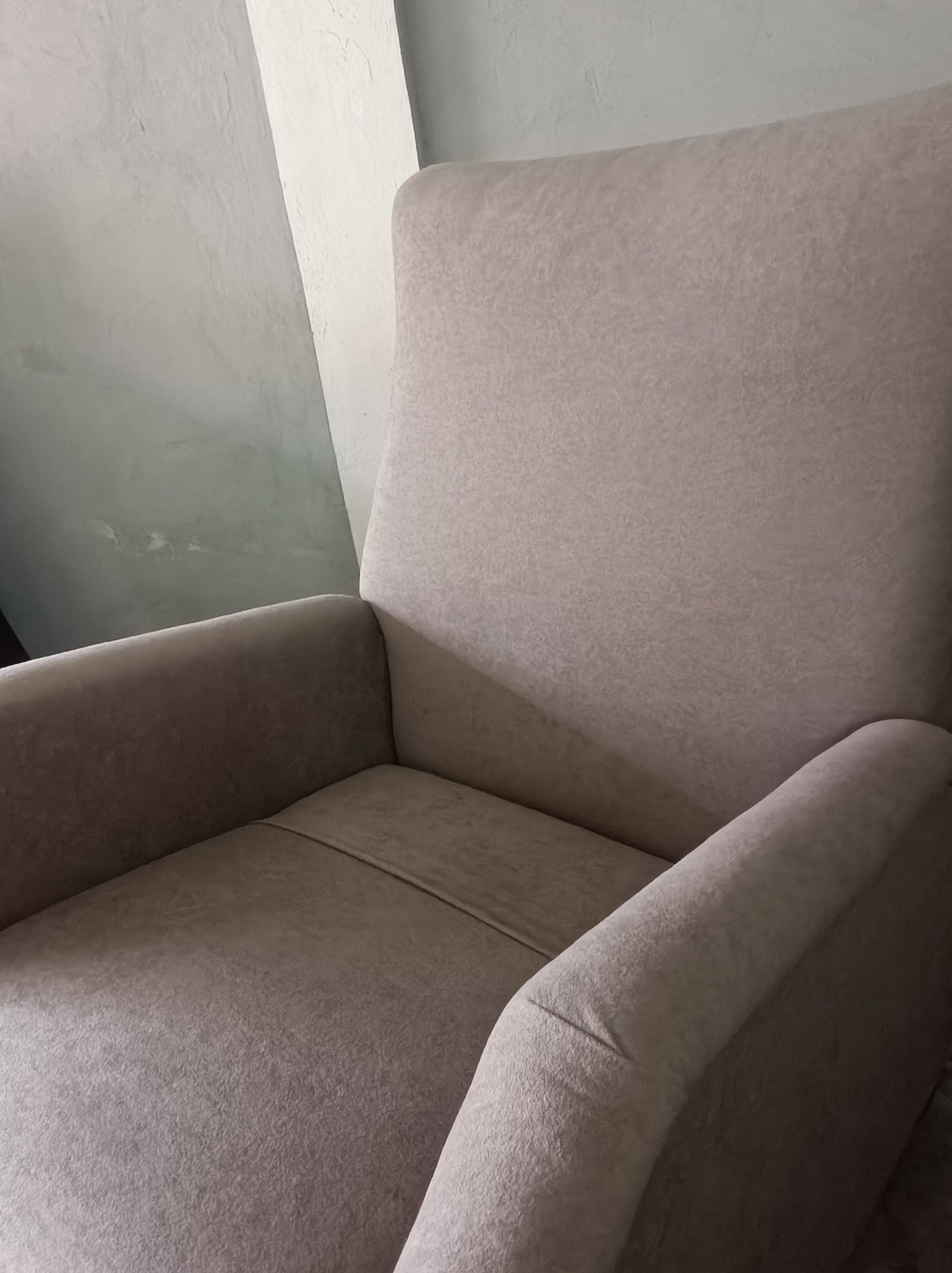 Kremowy fotel z wysokim oparciem, widoczny z bliska, prezentujący fakturę tapicerki w neutralnym oświetleniu.