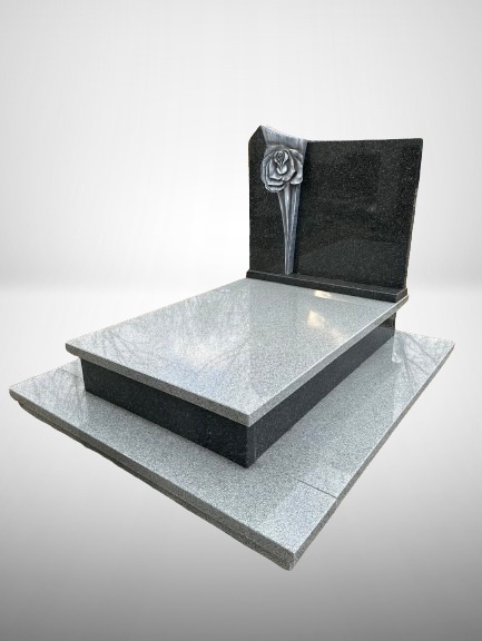 Dwupoziomowy pomnik z jasnoszarego granitu z ciemnoszarą tablicą ozdobioną srebrną, stylizowaną różą.