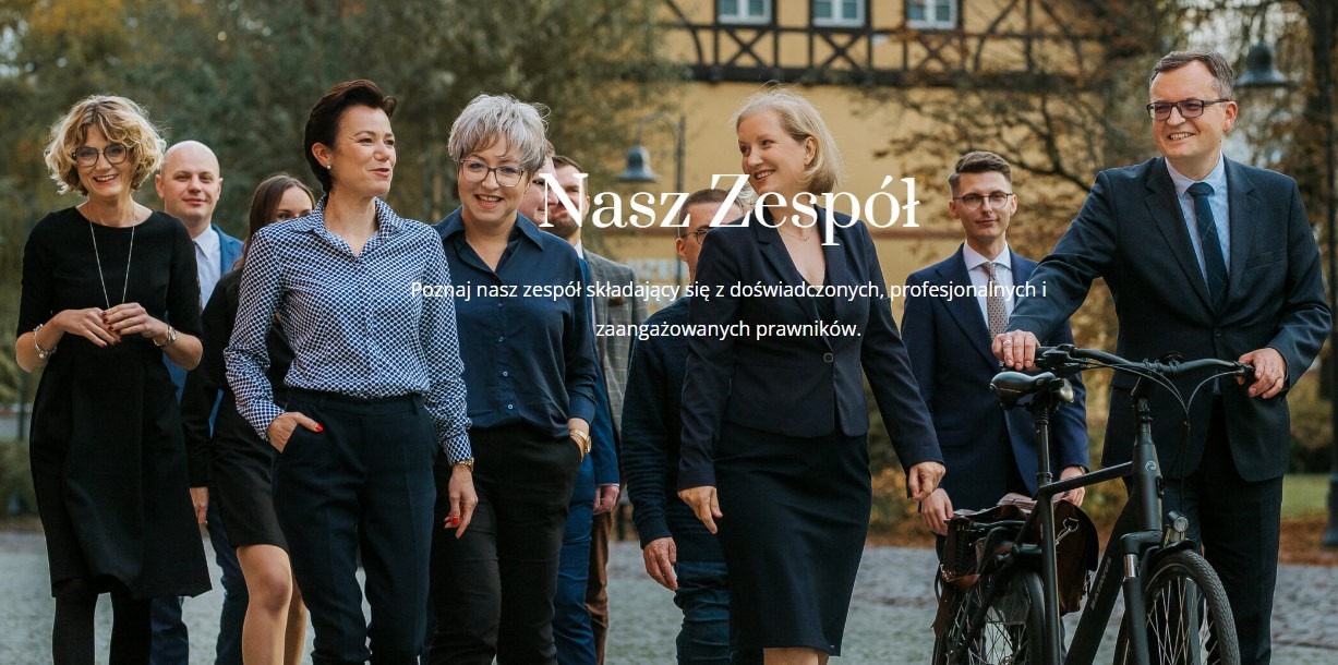 Zespół prawników kancelarii TEBI z Bydgoszczy, w tle budynek, jeden z prawników opiera rękę na rowerze.