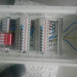 PROFI-ELEKTRO Usługi instalatorsko-eletryczne MARCIN ZIOBROŃ - Rozdzielnica elektryczna w białej obudowie z widocznymi zabezpieczeniami przepięciowymi DEHNguard, bezpiecznikami ABB, listwami zaciskowymi w kolorach niebieskim i zielonym oraz okablowaniem...