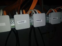 Szereg złączek elektrycznych z oznaczeniami SV8F7 i SV9F7, zamontowanych na szynie DIN, z widocznymi kablami w kolorze pomarańczowym i czarnym w tle.