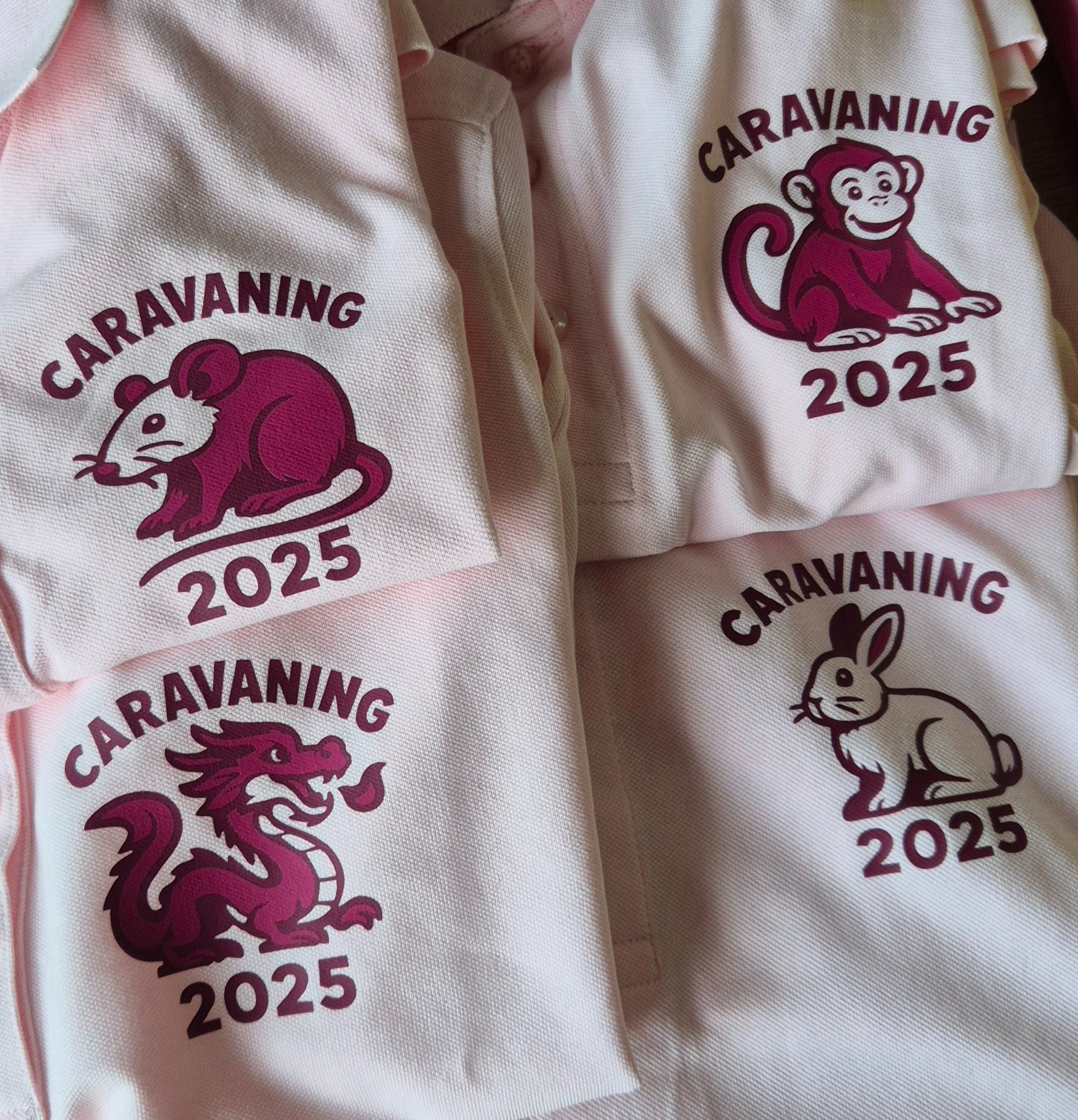 Jasnoróżowe koszulki polo z nadrukiem zwierząt (małpa, królik, smok, szczur) i napisem 'Caravaning 2025', ułożone warstwami, prezentacja gotowych produktów.