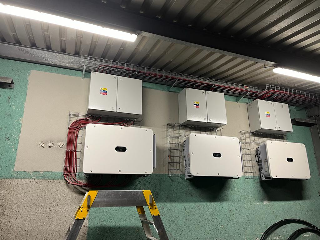 Montaż falowników w instalacji w Miękini, widoczne okablowanie i drabina monterska.