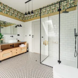 Nowoczesna łazienka z kabiną prysznicową ze szklanymi ścianami w czarnych ramach, białe płytki imitujące cegłę, wzorzysta tapeta na suficie, drewniana szafka pod umywalką i geometryczna podłoga.