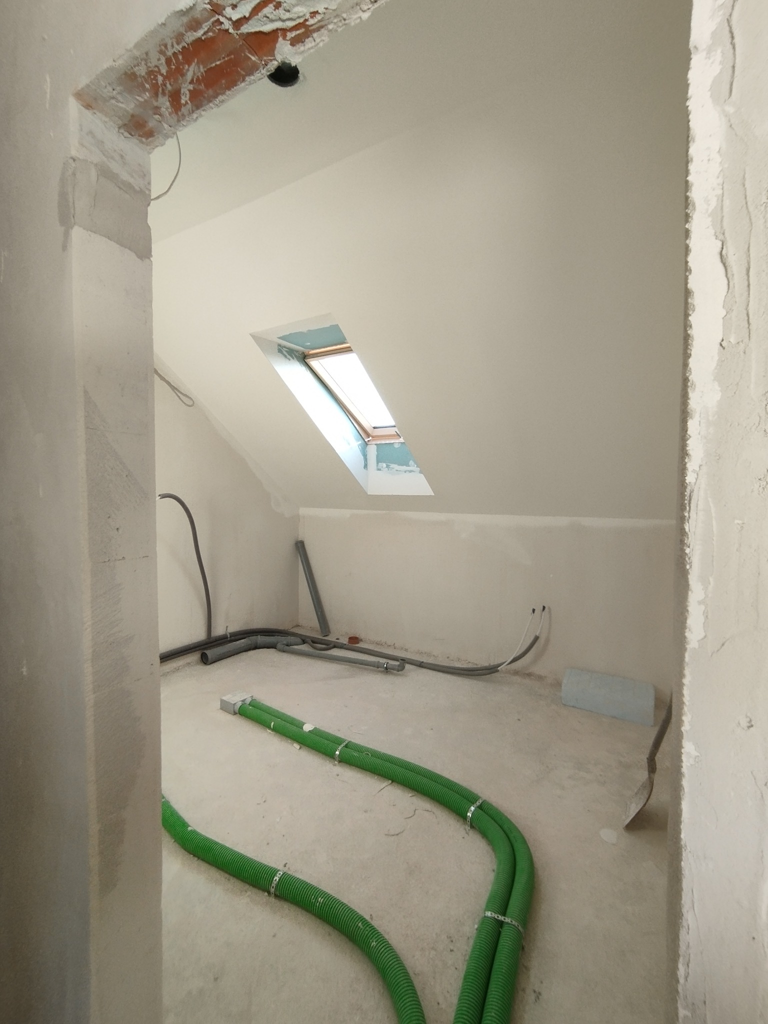 Poddasze w trakcie wykończenia w Krosno Odrzańskie: widoczne przewody wentylacyjne, okno dachowe i surowe ściany przygotowane do gładzi.