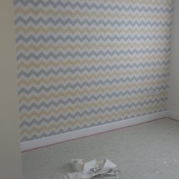 Tab-bud - Pokój w trakcie tapetowania w Ostrowie Wielkopolskim, widoczna ściana z wzorem w zygzaki, resztki tapety na podłodze.