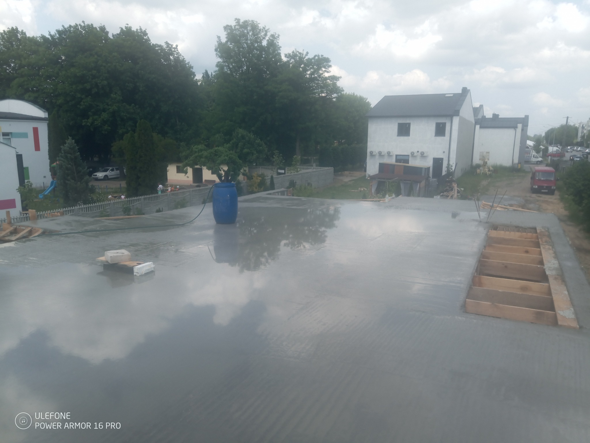 Świeżo wylana, mokra płyta fundamentowa z deskowaniem w Zadzimiu, odbijająca chmury na powierzchni.