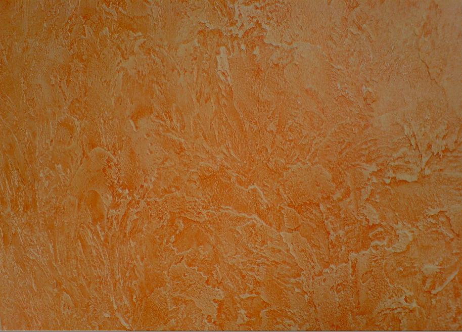 Pomarańczowa ściana pokryta dekoracyjnym tynkiem akrylowym o wyraźnej, nieregularnej fakturze, imitującej naturalny kamień lub trawertyn.