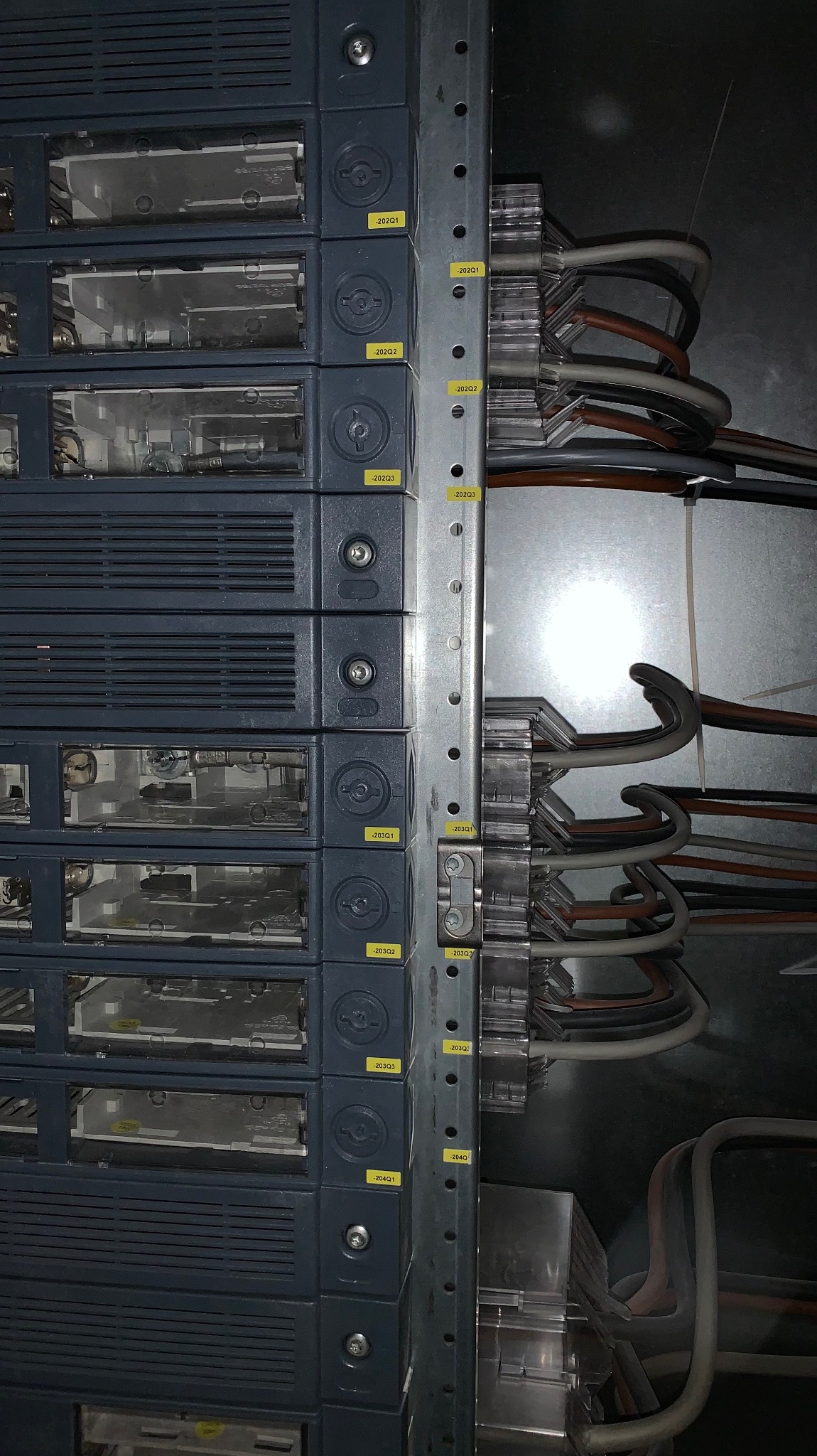 Szczegółowe ujęcie rozdzielnicy elektrycznej z oznaczonymi modułami i przewodami, widoczne numery identyfikacyjne na żółtych etykietach.