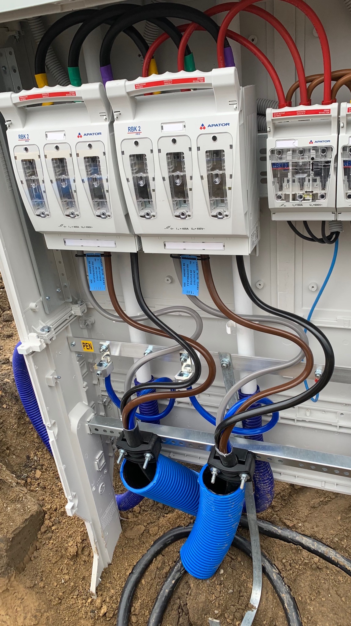 Rozdzielnia elektryczna APATOR RBK 2 PRO z przewodami w peszlach, zamontowana w skrzynce. Widoczne oznaczenia i złącza. Instalacja przyłącza elektrycznego.