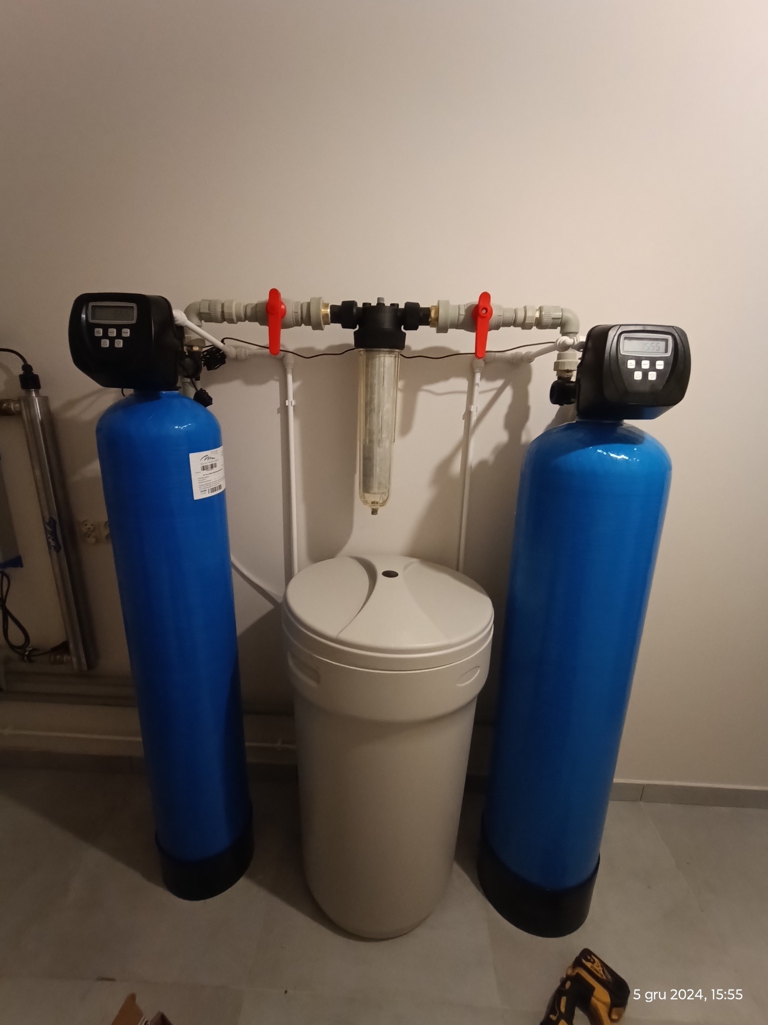 Kompletny system filtracji wody ze studni głębinowej: dwie niebieskie kolumny filtracyjne z elektronicznymi wyświetlaczami, filtr pośredni i kolumna ze złożem multifunkcyjnym.