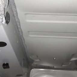 Autobezkorozji.pl - Widok podwozia samochodu na podnośniku, z widoczną warstwą zabezpieczenia antykorozyjnego i elementami zawieszenia.