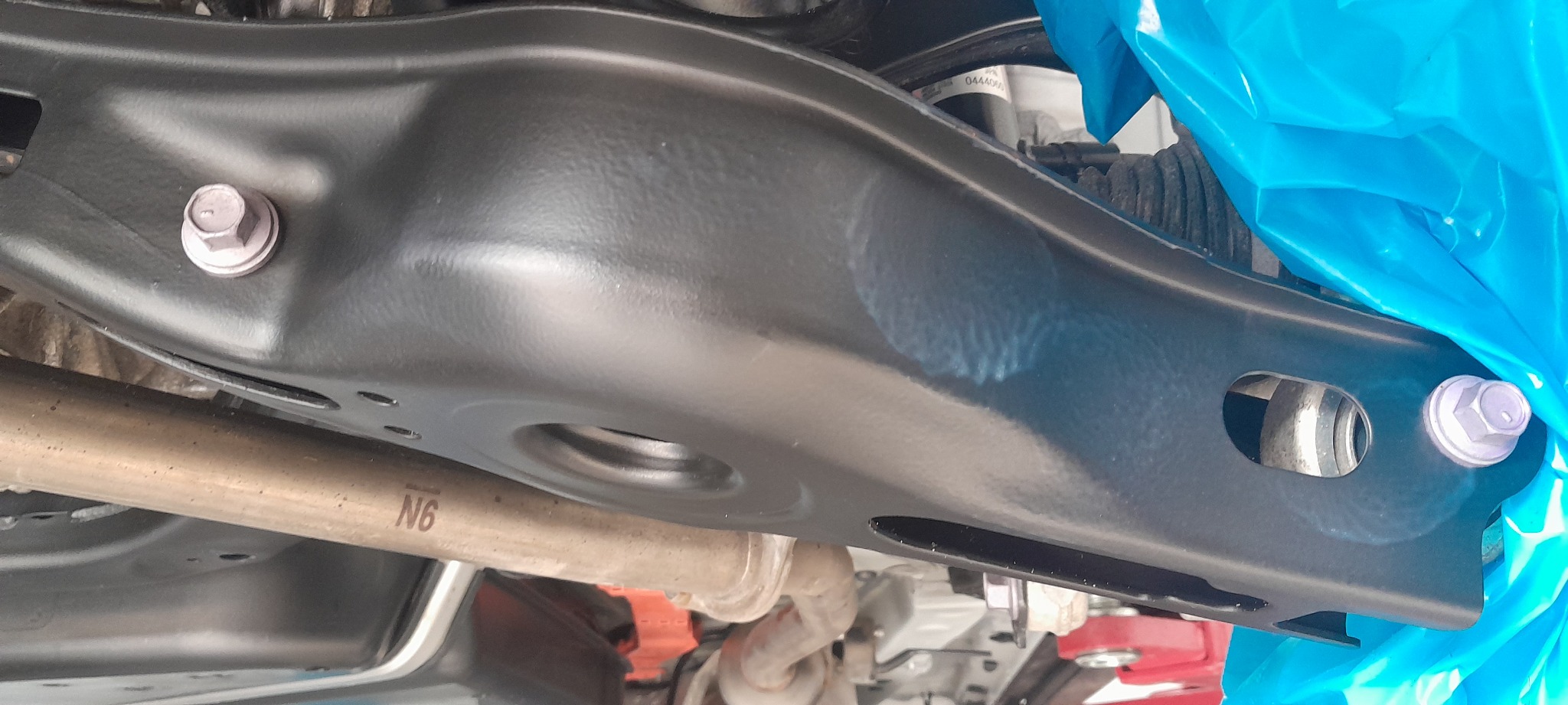 Podwozie samochodu po zabiegu antykorozyjnym w Janowie, widoczne nowe śruby i elementy zawieszenia zabezpieczone folią.