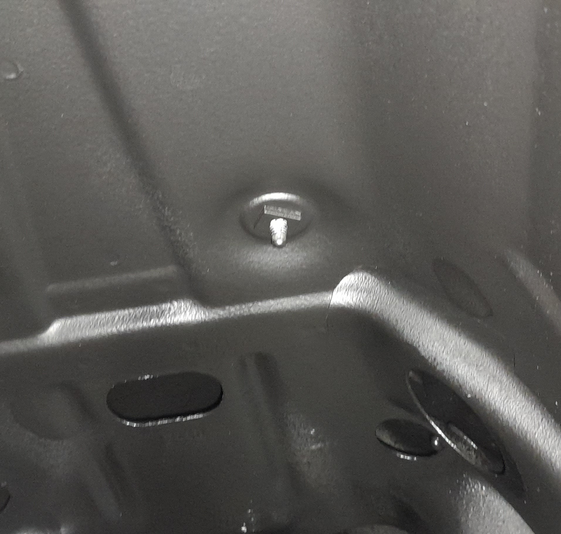 Wnętrze elementu karoserii pojazdu po piaskowaniu, widoczna czysta, szorstka powierzchnia metalu i śruba mocująca.