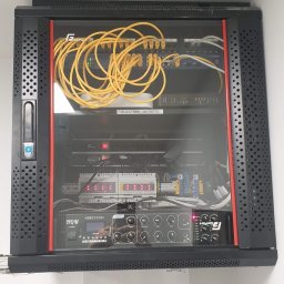 ES-COM SERVICE SPÓŁKA Z OGRANICZONĄ ODPOWIEDZIALNOŚCIĄ - Zamknięta szafa rack z widocznymi kablami ethernet, routerem WiFi z naklejką 'KLUCZ WIFI: 286226775', modułami sterującymi i wzmacniaczem HQM2350BC oraz GetFort GS7241.