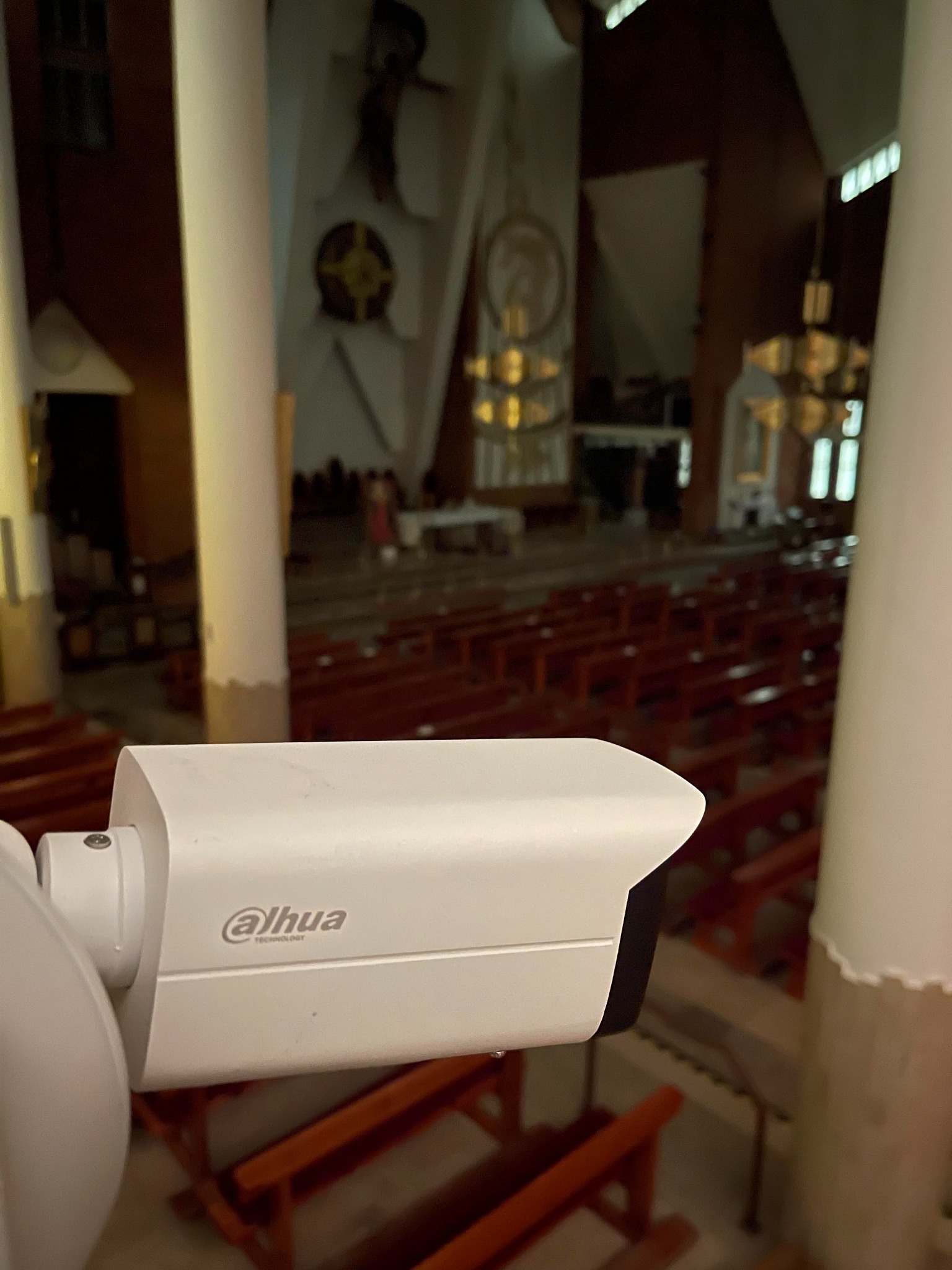 Kamera monitoringu Dahua zamontowana wewnątrz kościoła, widok na ławki i ołtarz w tle.