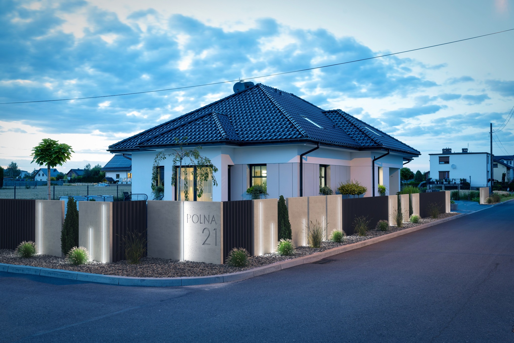 Nowoczesny dom jednorodzinny z ciemną dachówką i minimalistycznym ogrodzeniem z podświetleniem LED, adres 'POLNA 21' na betonowym elemencie ogrodzenia, widok z ulicy o zmierzchu.