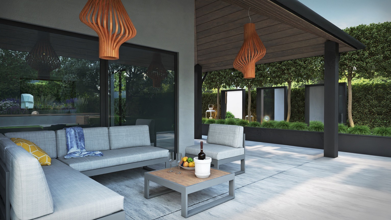 Zadaszony taras z szarymi meblami wypoczynkowymi, drewnianym stolikiem kawowym z owocami i schłodzonym winem, oświetlony dekoracyjnymi, ażurowymi lampami wiszącymi z drewna.