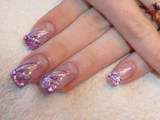 Delikatne tipsy kwadratowe z fioletowym brokatem i subtelnym wzorem, na tle kremowej tkaniny.