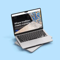 Laptop unoszący się nad drugim laptopem, na ekranie strona internetowa z portugalskimi motywami ceramicznymi i tekstem 'Where tradition meets mastery'.