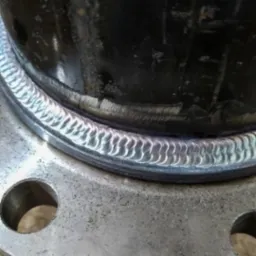 Spoina obwodowa rury stalowej do kołnierza, widoczna struktura spoiny i ślady obróbki na kołnierzu.