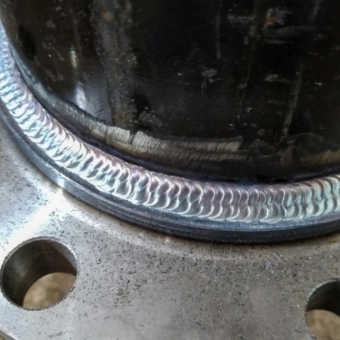 Spoina obwodowa rury stalowej do kołnierza, widoczna struktura spoiny i ślady obróbki na kołnierzu.