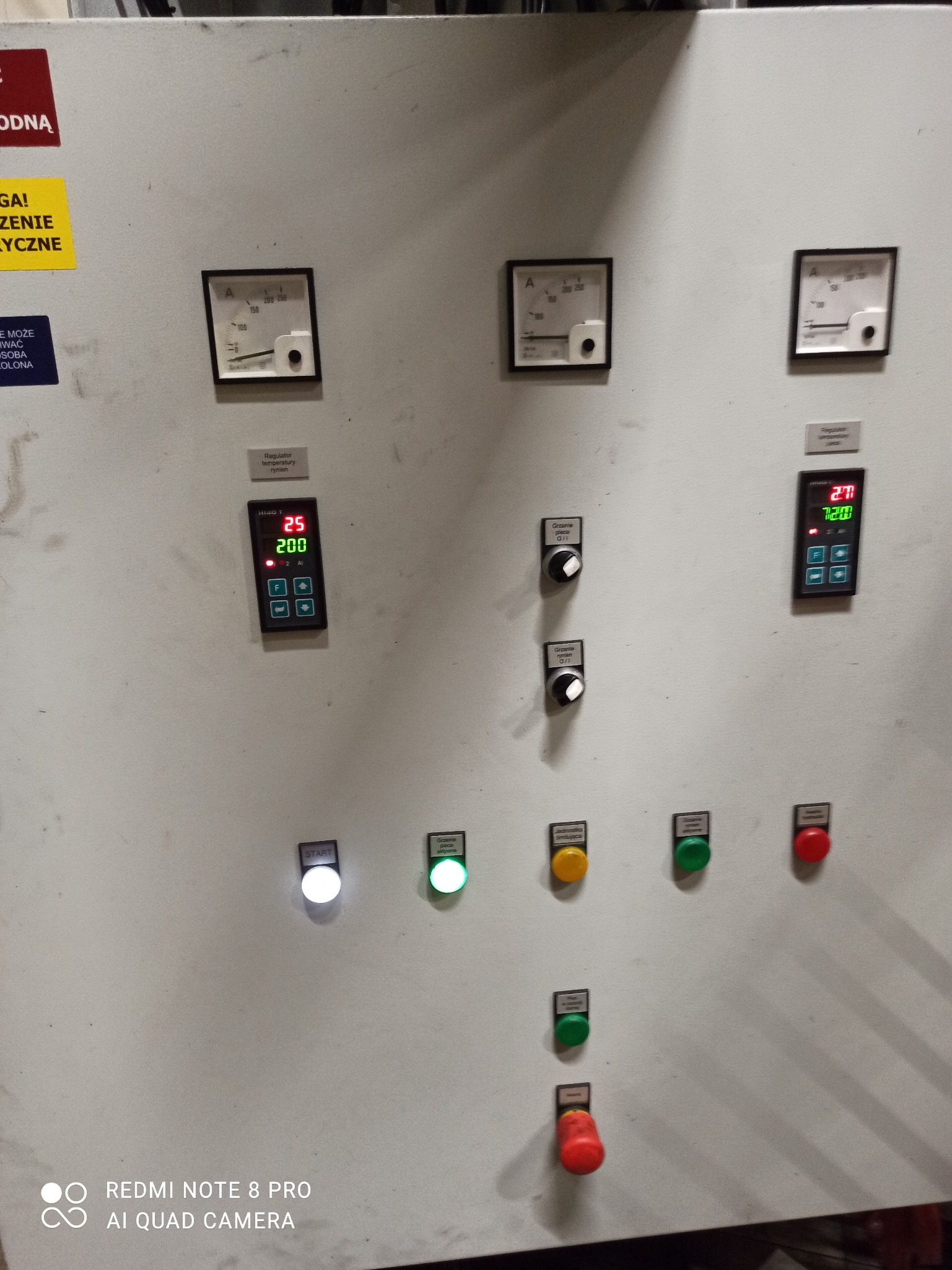 Szary panel sterowania urządzeniem elektrycznym w Lublinie, z analogowymi amperomierzami, cyfrowymi wyświetlaczami temperatury i serią podświetlanych przycisków oraz pokręteł regulacyjnych.