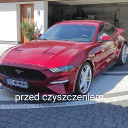 CZYSTY DOM I SAMOCHÓD - MARCIN KWAPISZ - Czerwony Ford Mustang zaparkowany na kostce brukowej przed garażem, widoczny numer rejestracyjny SO MMMMM.
