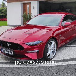 CZYSTY DOM I SAMOCHÓD - MARCIN KWAPISZ - Czerwony samochód sportowy Ford Mustang zaparkowany na kostce brukowej przed garażem, widoczne detale karoserii po czyszczeniu, tablica rejestracyjna SO MMMMMM.