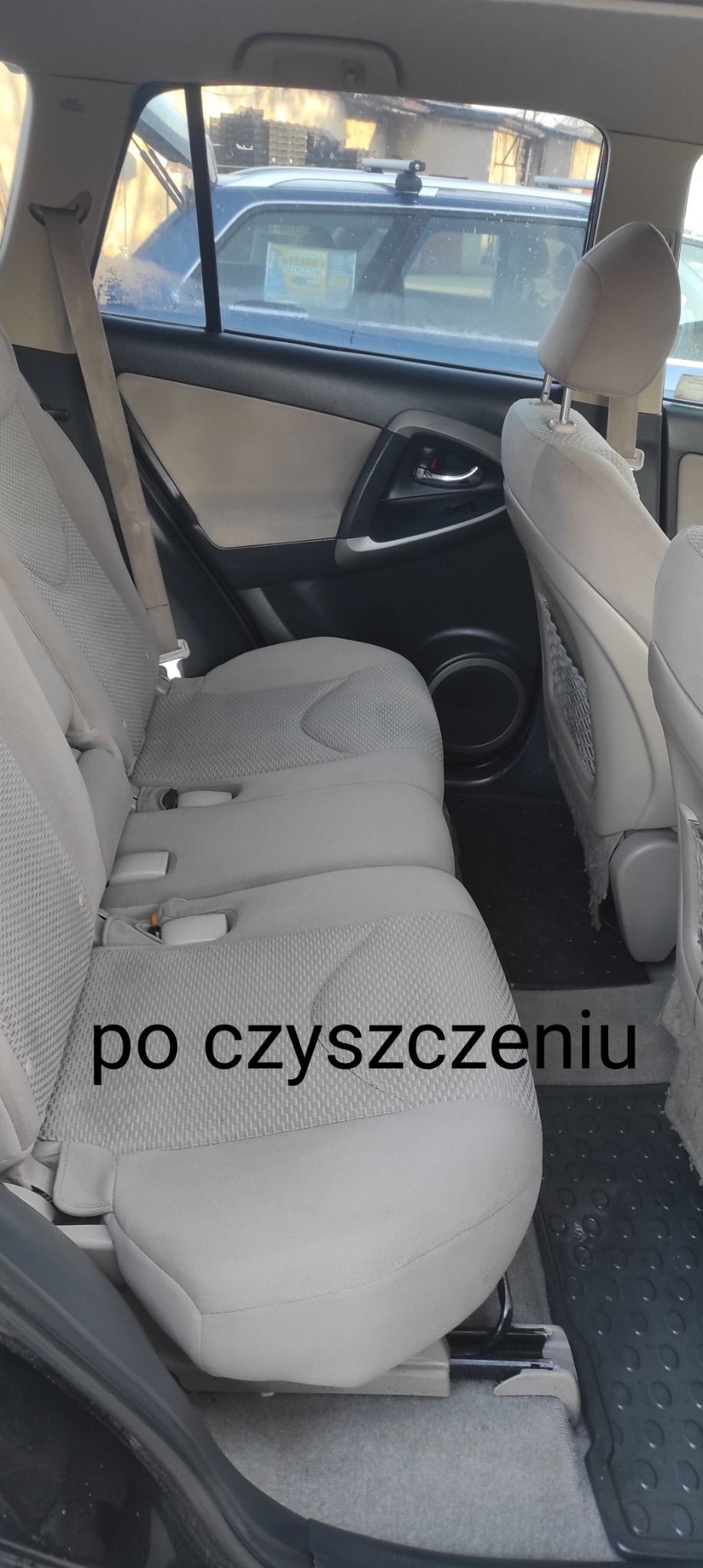 Jasna, wyczyszczona tylna kanapa samochodu marki Toyota RAV4, widok z boku, na podłodze czarne gumowe dywaniki.