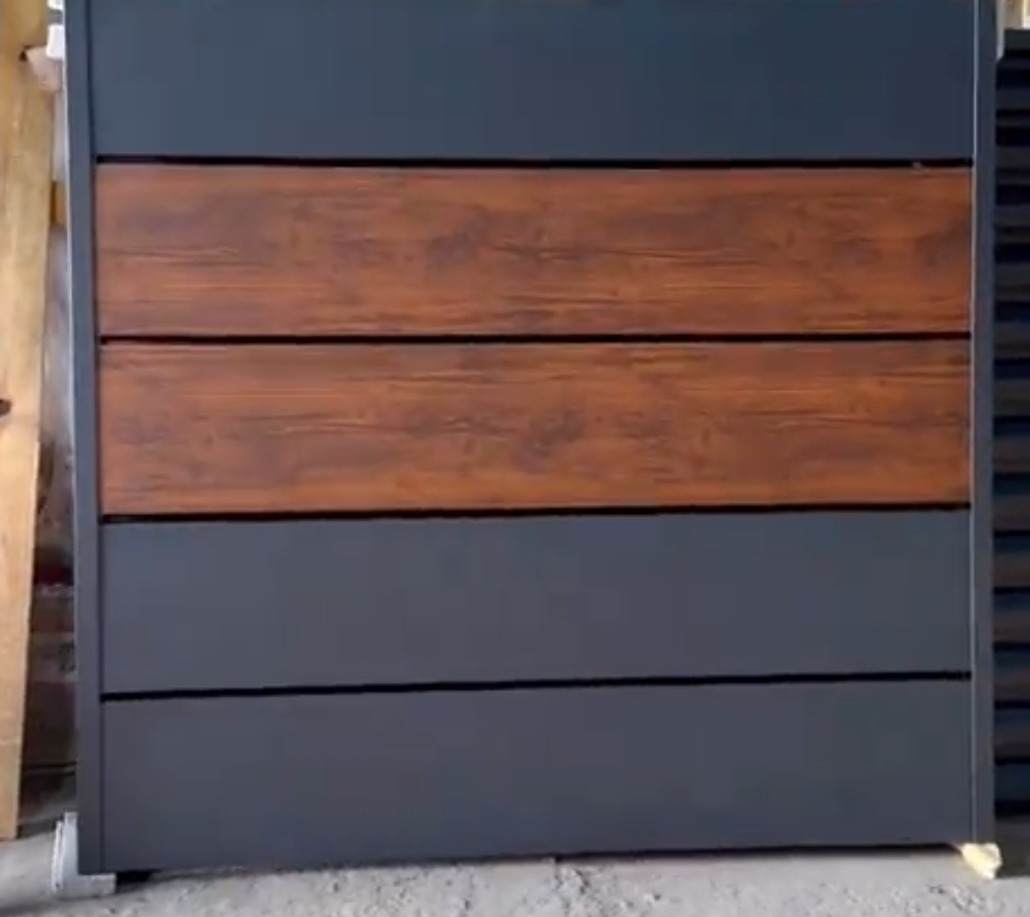 Nowoczesny fragment ogrodzenia panelowego z poziomymi przęsłami: szare obramowanie i wypełnienie z imitacji drewna.