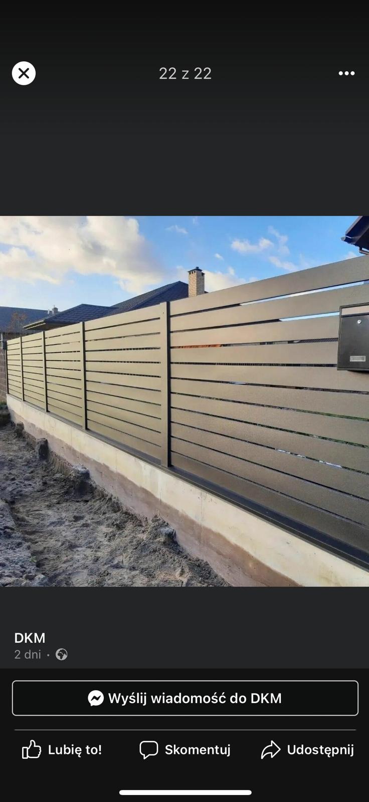 Nowoczesne, poziome panele tworzące ogrodzenie posesji w kolorze grafitowym, z widoczną skrzynką pocztową i fundamentem w trakcie wykończenia.