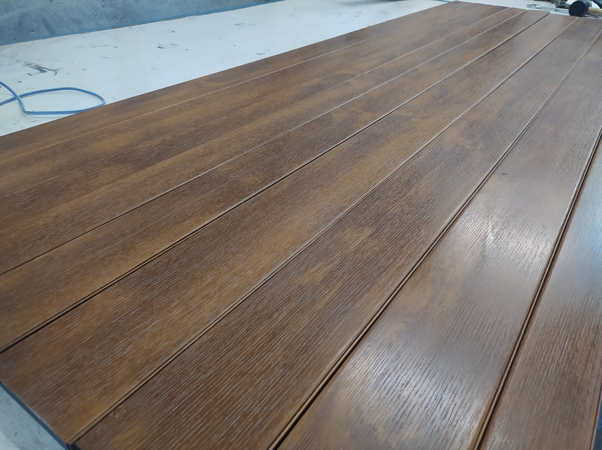 Panel ogrodzeniowy metalowy z widoczną strukturą drewna, leżący na szarym podłożu, przygotowany do montażu.