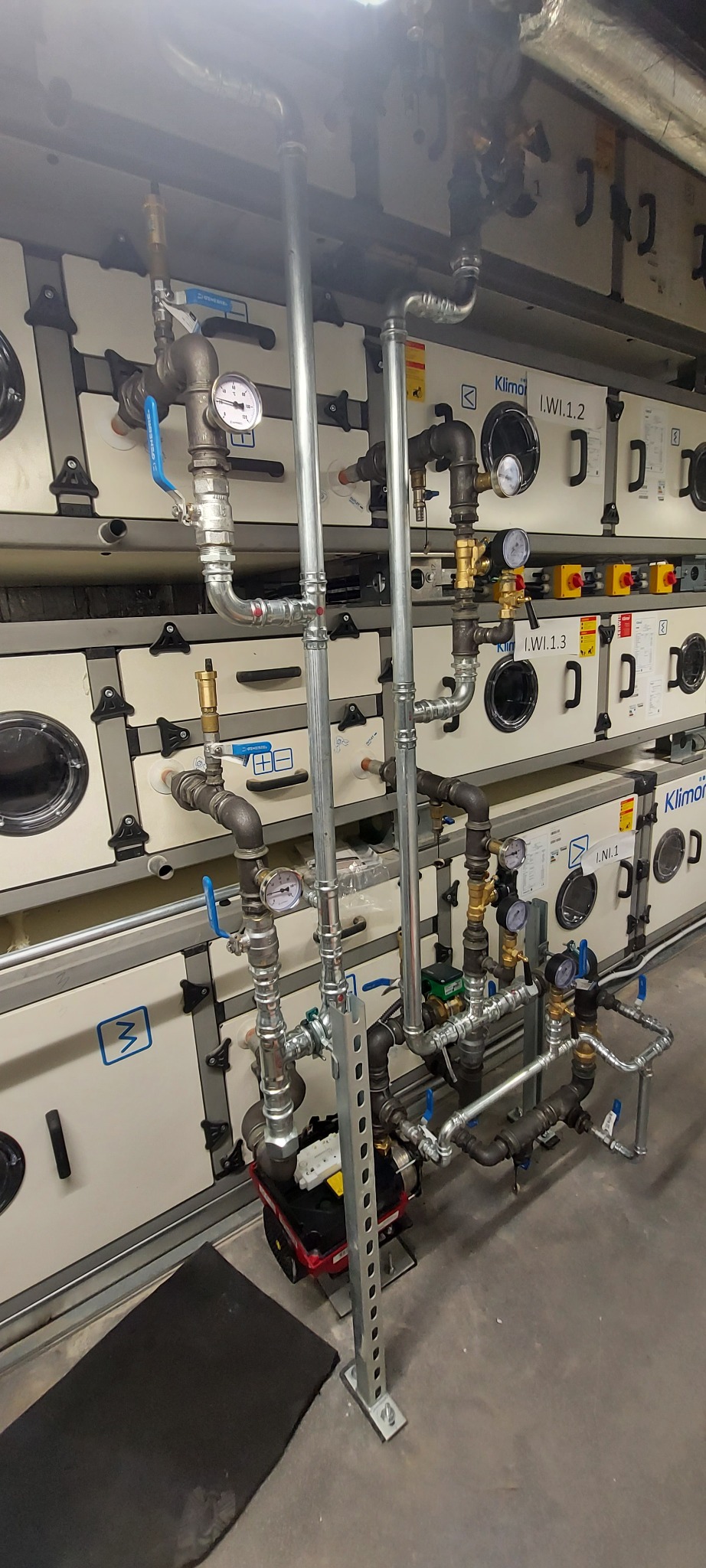 Złożony system rur z manometrami i zaworami, zainstalowany przy urządzeniach Klimor I.WI.1.2 i I.WI.1.3, widok z bliska na instalację hydrauliczną.