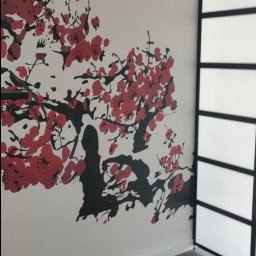 Usługi remontowo budowlane Pablobud Paweł Janowski - Ściana z dekoracyjnym malunkiem kwitnącej wiśni w kolorach czerwieni i czerni, uzupełniona o przesuwne drzwi w stylu japońskim z czarną ramą i mlecznym szkłem.