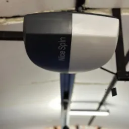 Zamontowany napęd do bramy garażowej Nice Spin, widok od dołu, z widoczną szyną prowadzącą i elementami konstrukcyjnymi sufitu garażu.