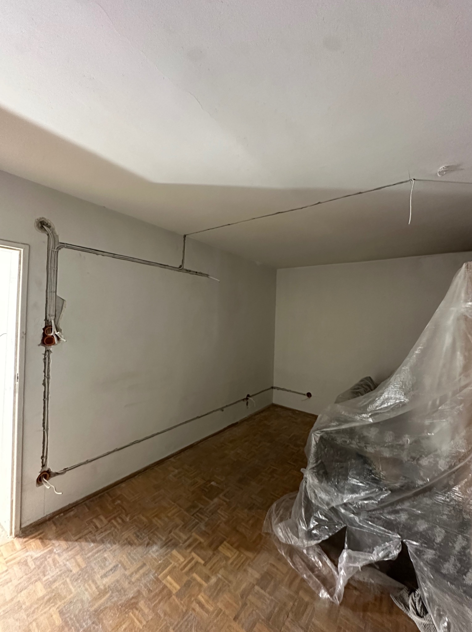 Instalacja elektryczna w trakcie montażu w Olszewnicy Starej. Widoczne kable prowadzone po ścianach i suficie, przygotowane do podłączenia gniazdek i oświetlenia.