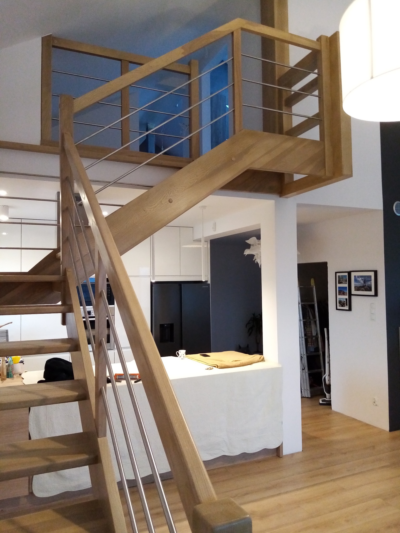 Nowoczesne schody z drewna i metalu z balustradą ze stalowych prętów w jasnym wnętrzu domu.