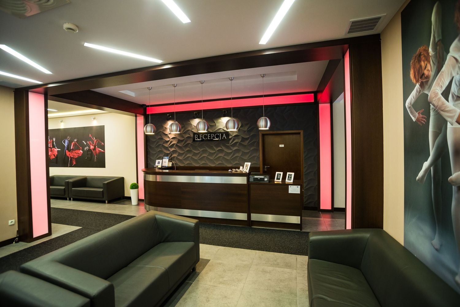 Nowoczesne oświetlenie LED w recepcji: podświetlane panele ścienne, lampy wiszące i listwy sufitowe tworzą ciepłą atmosferę.