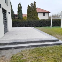 Taras na ogrodzie z kostki betonowej dekoracyjnej wraz ze stopnicami schodowymi.