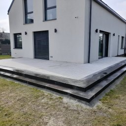 Taras na ogrodzie z kostki betonowej dekoracyjnej wraz ze stopnicami schodowymi.