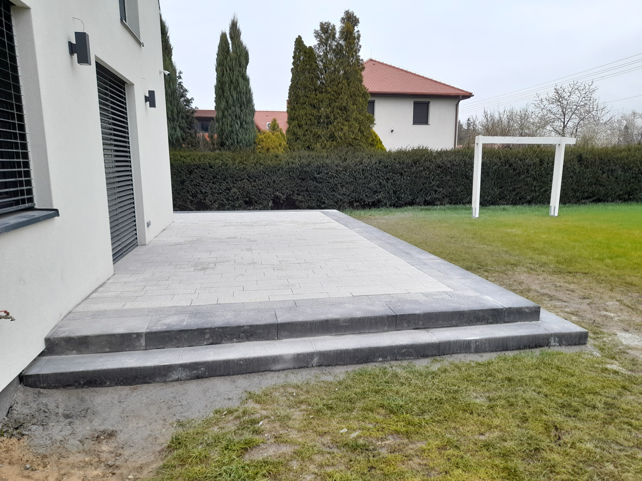 Taras na ogrodzie z kostki betonowej dekoracyjnej wraz ze stopnicami schodowymi.