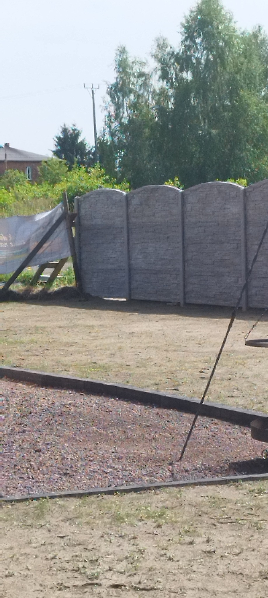 Fragment budowy ogrodzenia z prefabrykatów betonowych; widoczne elementy konstrukcyjne i zabezpieczające teren budowy.