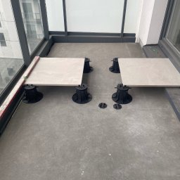 Igor Martsynkovskyi - Układanie płytek na regulowanych wspornikach na balkonie, widoczny poziomica i ołówek, etap prac wykończeniowych.