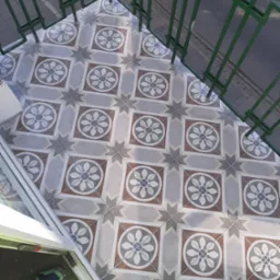 Nowa, wzorzysta podłoga z płytek na balkonie, widok z góry, zielona metalowa balustrada, fragment buta w jaskrawym kolorze przy drzwiach balkonowych.