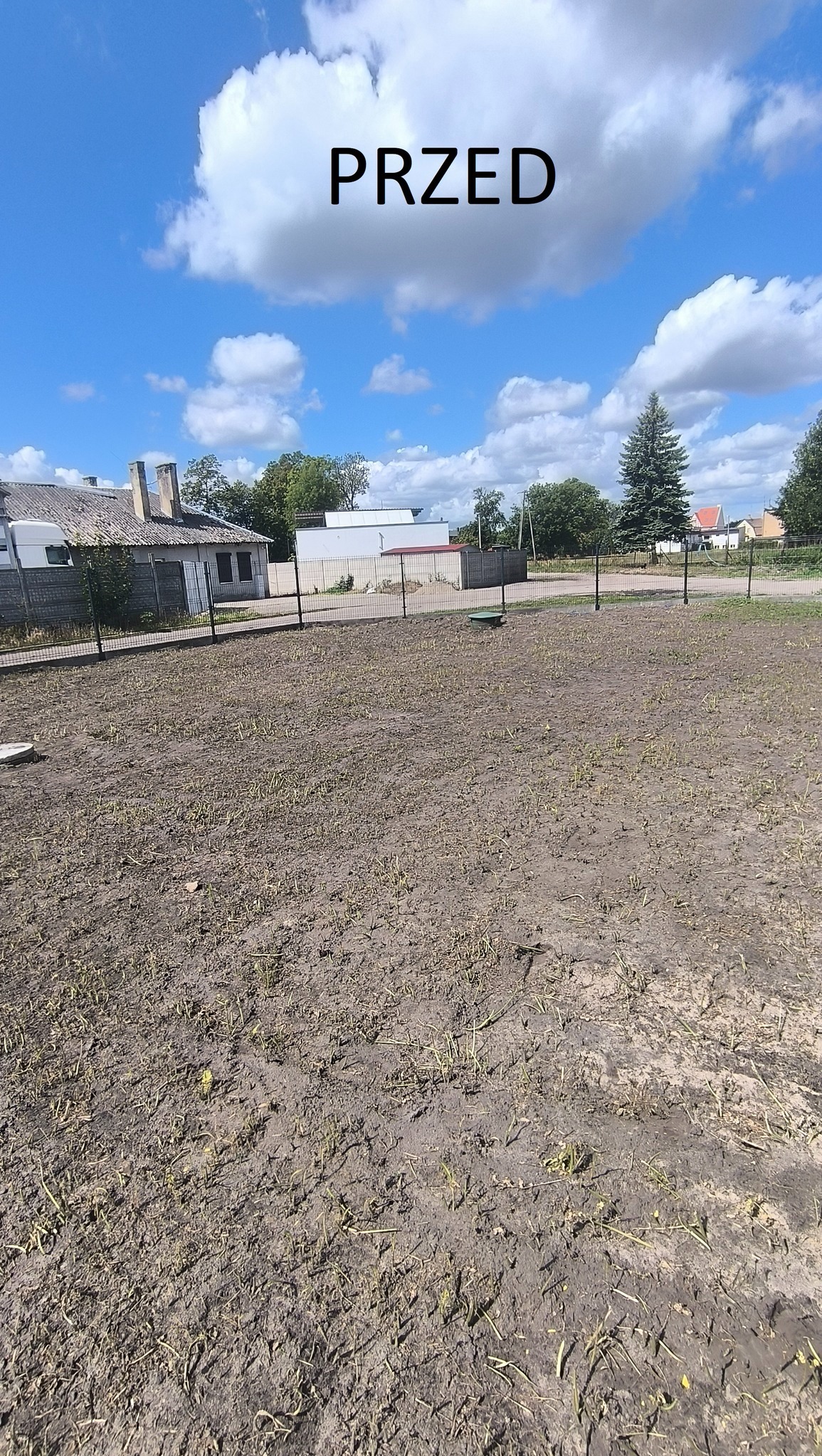 Zdjęcie ukazuje przygotowany teren pod przyszły ogród, z widoczną siatką ogrodzeniową w tle i resztkami roślinności. Fotografia typu 'przed' z dodanym napisem PRZED.